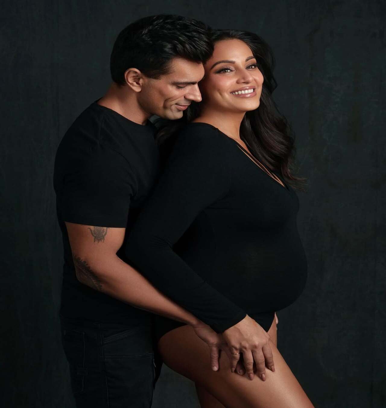 This pregnancy photoshoot is sizzling yet heartwarming! Dressed in black, the mom-to-be flaunts her baby bump and a wide smile, while Karan embraces her from behind and places an arm on her thigh